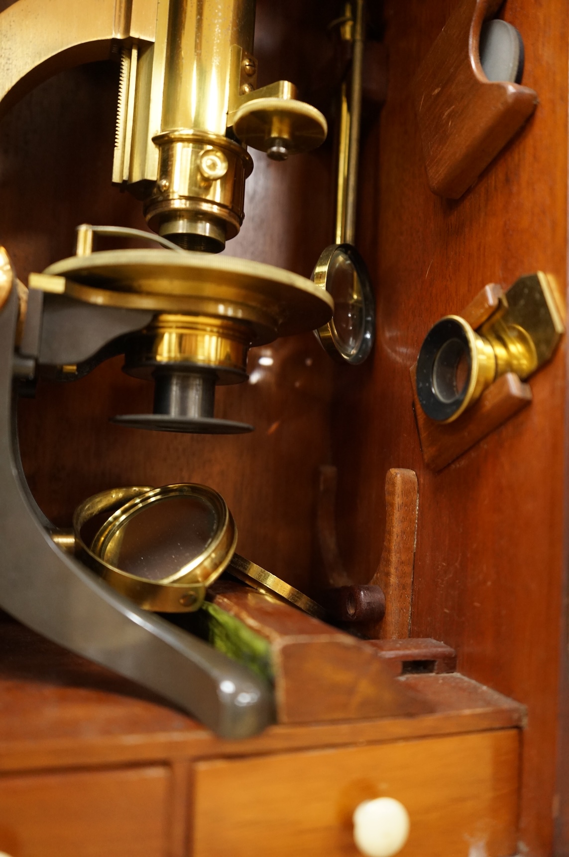 A Victorian binocular brass microscope, unsigned, in a fitted, glass fronted case with a good selection of alternative lenses and accessories, all in fitted compartments, plus three integral drawers to hold microscope sl